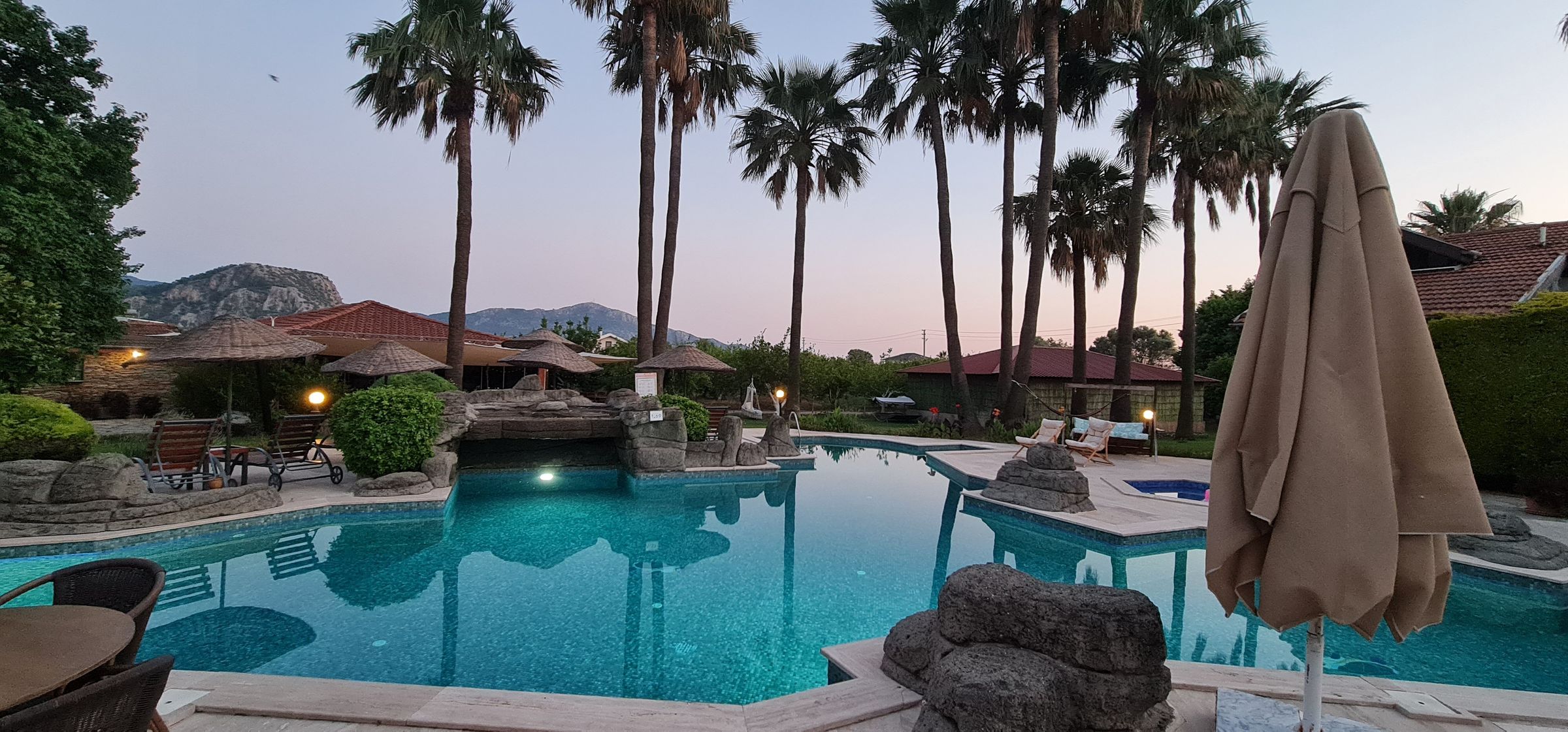 Abendstimmung am Pool der Lodge, Palmen vor den Bergen